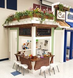 a small booth with plants on the roof and chalkboard writing on the wall behind it