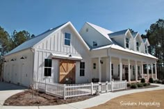 a large white house with lots of windows on it's sides and a picket fence around the front yard