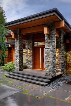 a modern house with stone pillars and wood trim around the front door, on a rainy day