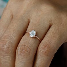 a woman's hand with a diamond ring on her finger, showing the center stone