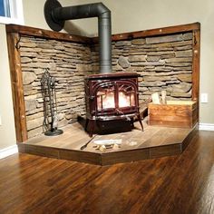 a wood burning stove sitting on top of a hard wood floor in front of a stone wall