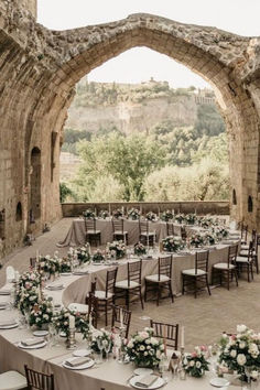 an outdoor venue with tables and chairs set up for a formal function in the stone archways