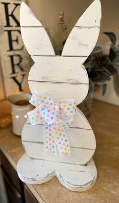 a white wooden bunny with polka dot bow on it's head sitting on top of a counter