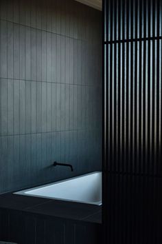 a black and white photo of a bathtub in a bathroom with dark wood slats on the walls