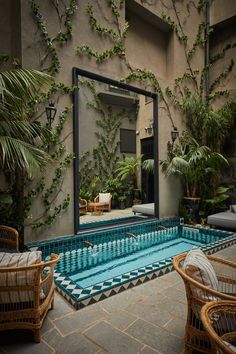 an indoor swimming pool surrounded by wicker chairs and tables with mirrors on the wall