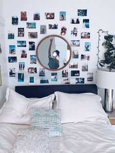 a bed with white sheets and pillows in front of a wall with pictures on it