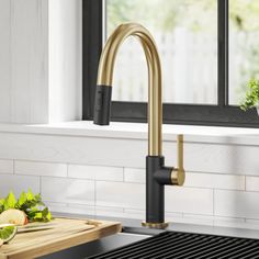 a kitchen sink with a black and gold faucet next to a cutting board