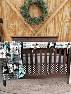 a baby crib with a wreath on the wall next to it and some blankets