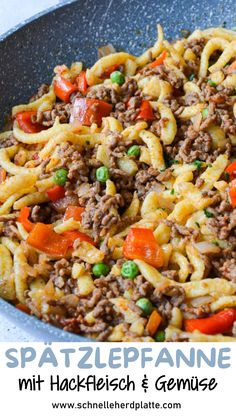 a skillet filled with pasta, meat and veggies on top of a table