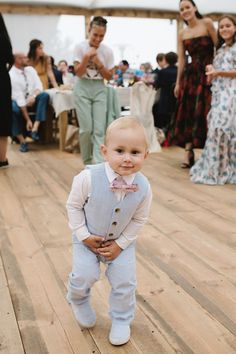 a little boy that is standing in the middle of a floor with people around him