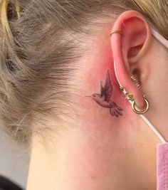 a woman with a humming tattoo behind her ear