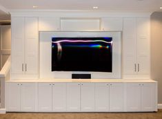 a large flat screen tv mounted to the side of a white wall in a living room