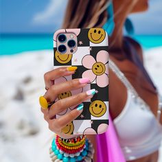 a woman holding up her phone case with smiley faces on it