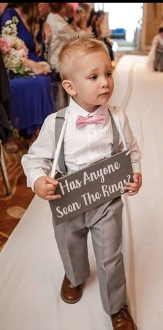 a little boy in a suit and bow tie holding a sign that says, has anyone seen the rings?