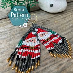 a pair of beaded santa clause earrings on top of a wooden table next to a potted plant