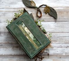 an old book is sitting on the floor next to some leaves and twigs that are growing out of it