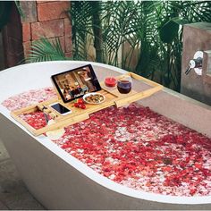 a bathtub filled with rose petals and an ipad