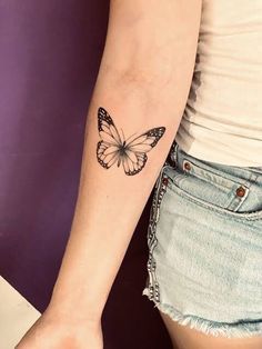 a woman's arm with a butterfly tattoo on the left side of her arm