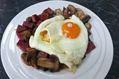 an egg is sitting on top of some mushrooms and other food items in a white plate