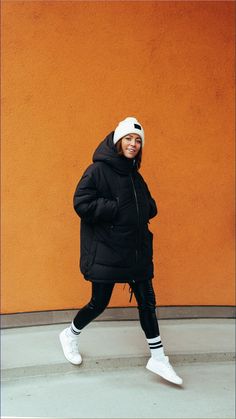 sporty outfit, streetstyle outfit, puffer jacket, black puffer jacket, winter look, winter fashion trend, orange background, acne beanie, outfit inspo, outfit ideen, women streetstyle look, outfit inspiration, fashion blogger, streetstyle blogger, german fashion blogger, bloggerstyle, all black outfit, woman style, Winter 2021 Winter Trainers Outfit, Aritzia Superpuff Long Outfit, Beanie Women Outfit, Winter Outfit With Hat, Beanie Looks Street Styles, Black Winter Jacket Outfit, Longline Puffer Jacket Outfit, Winter Outfits Cold Aesthetic, German Winter Outfits