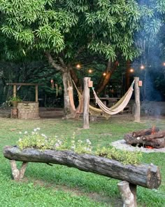 a wooden bench sitting in the middle of a lush green field next to a fire pit