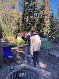 two people standing in front of a campfire