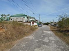 a car parked on the side of a dirt road next to houses and power lines