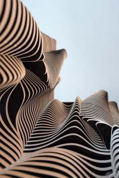 an abstractly designed sculpture with wavy lines on it's sides, against a blue sky