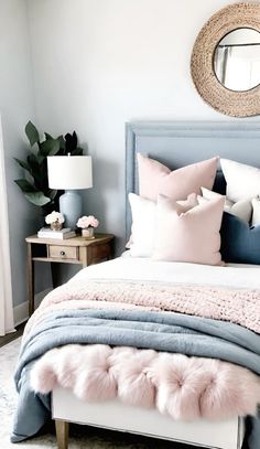 a bed with pink and blue pillows on top of it next to a mirror above the bed