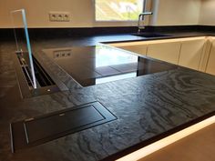 a black counter top in a kitchen next to a sink and window with no curtains