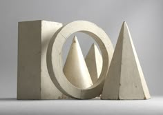 an abstract sculpture made out of concrete with three different shapes in the middle and one behind it