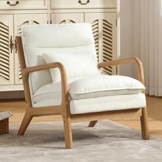 a white chair sitting on top of a wooden floor next to a dresser and drawers