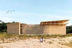 two children are playing in the sand near a building that is made out of wood