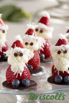 some strawberries and blueberries with santa clause on them sitting on a glass plate