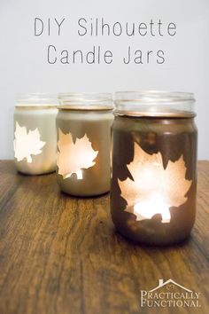 three mason jars filled with candles sitting on top of a wooden table