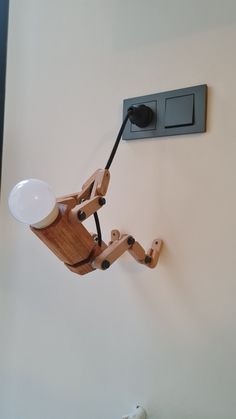 a wooden robot is hooked up to a light switch on the wall by a cord