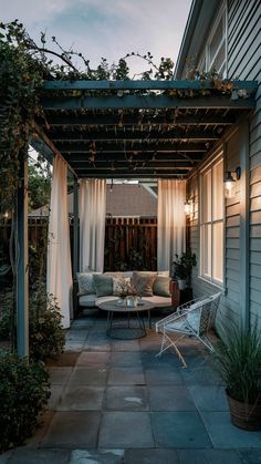 a patio covered in curtains and furniture next to a building