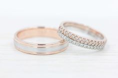 two white and rose gold wedding bands with diamonds on them, sitting side by side