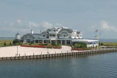 a large white house sitting on top of a lush green field next to the ocean