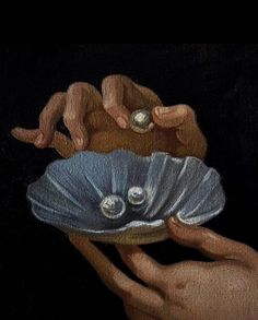 two hands holding a shell with pearls on it