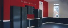 an empty room with three refrigerators and a table in front of the wall that says porsche