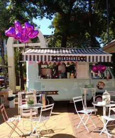 an ice cream truck is parked on the side of the road near tables and chairs