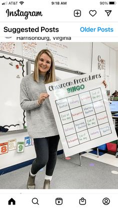 a woman holding up a sign in front of a classroom