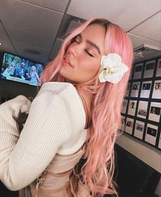 a woman with pink hair and a flower in her hair is posing for the camera