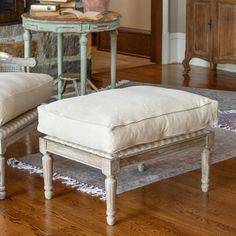 a chair and ottoman sitting on top of a hard wood floor next to a table