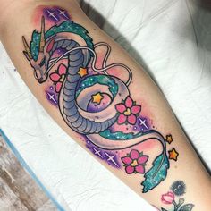 a colorful tattoo design on the arm of a woman's left leg, with a dragon and flowers