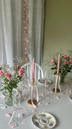 the table is set with pink flowers and candles