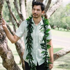 a man standing next to a tree wearing a lei