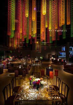 a dining room filled with lots of tables and chairs under colorful chandelier hanging from the ceiling