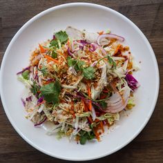 a white plate topped with lots of veggies on top of a wooden table